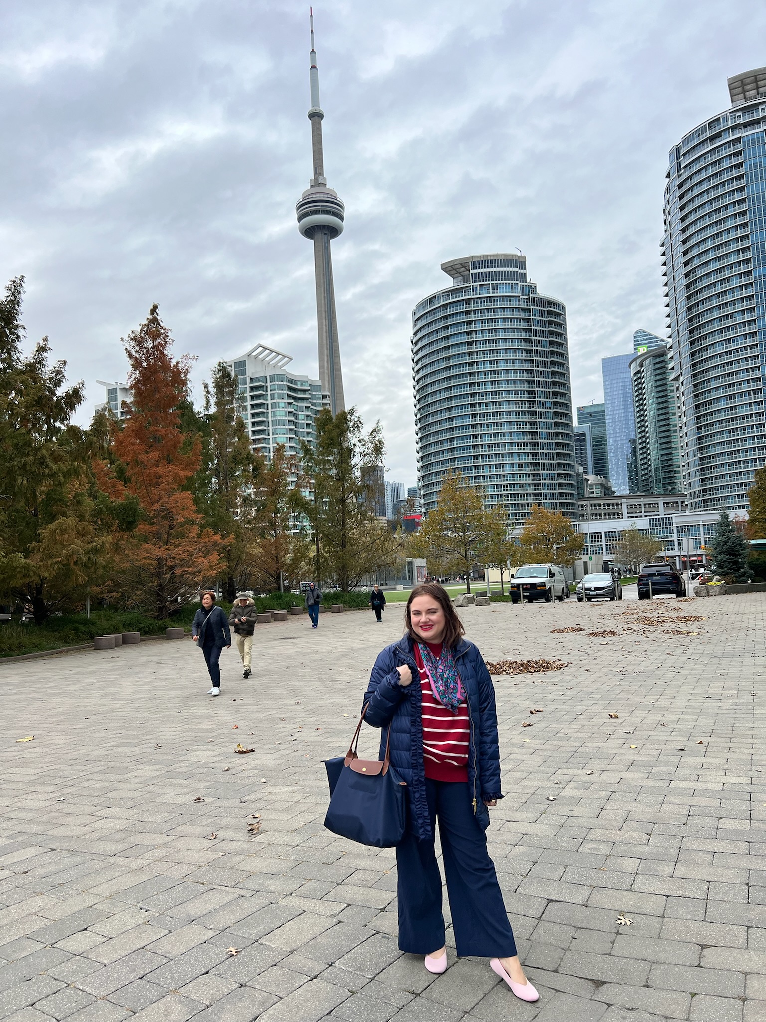 Fall Preppy Outfits Pink Chickadee in a red and white striped shirt, blue puffer vest, wide-leg trousers paired with a silk scarf