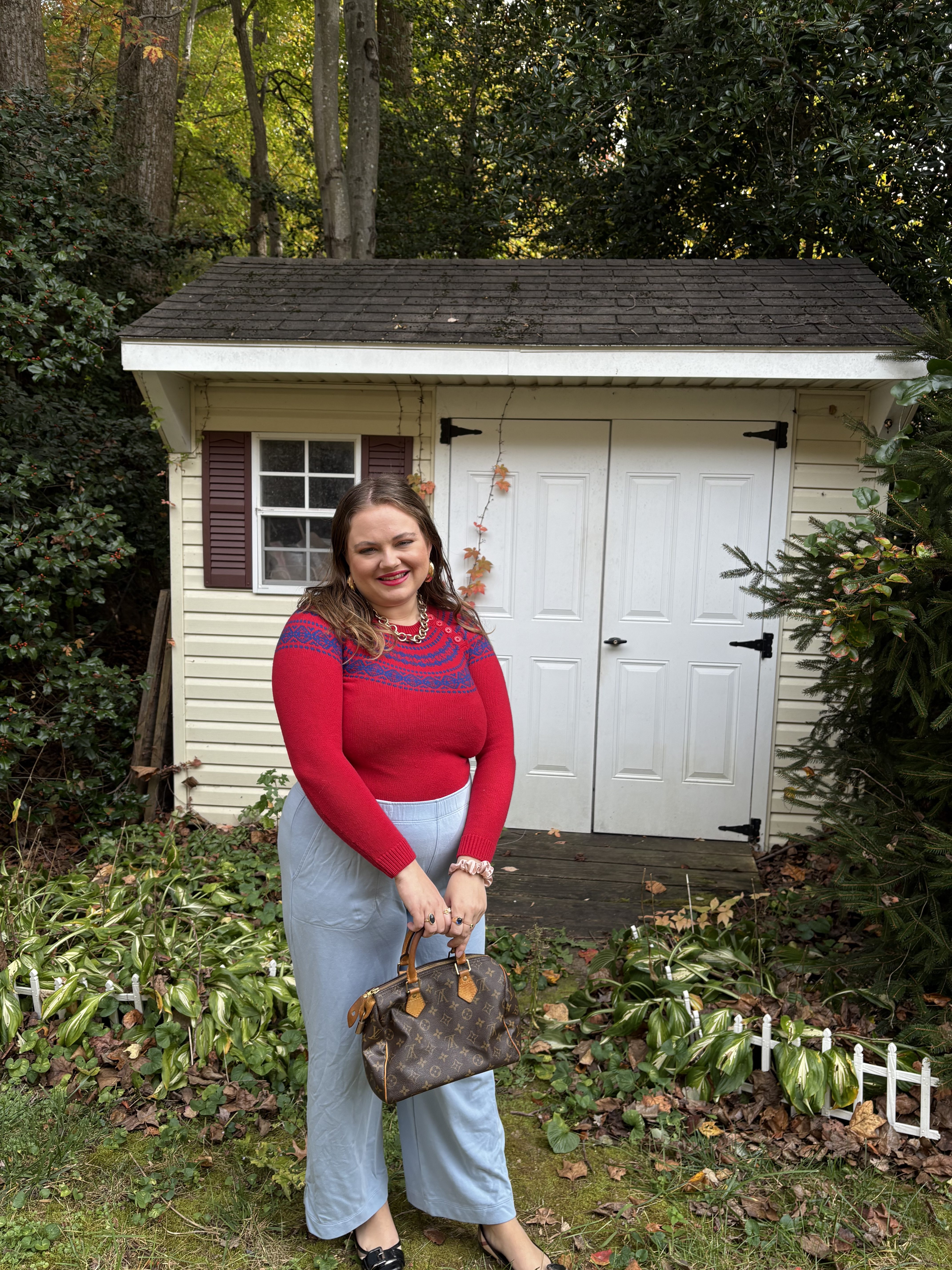 Fall Preppy Outfits Pink Chickadee wearing a red sweater with blue horizontal stripes, light-wash wide-leg jeans, and holding a Louis Vuitton monogram handbag