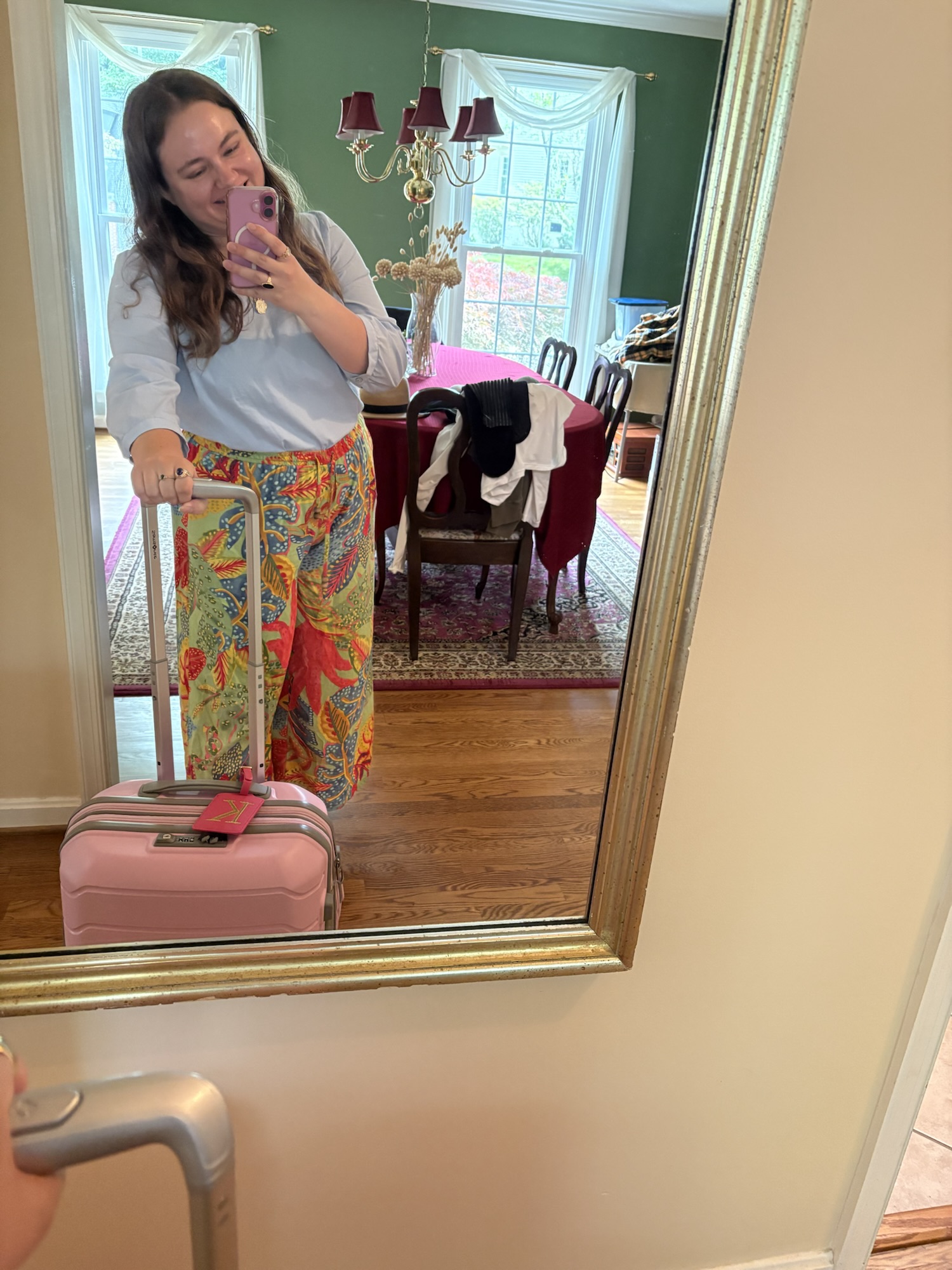 Pink Chickadee wearing a preppy outfit: short-sleeved light blue button-down shirt tucked into vibrant, orange and pink tropical floral wide-leg pants