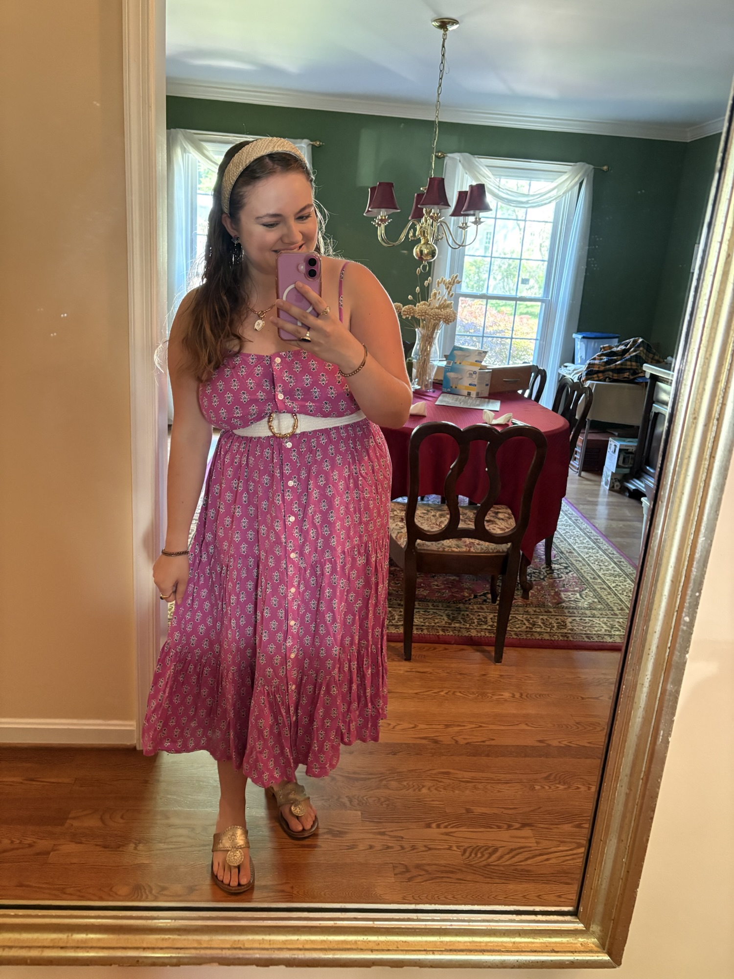 Pink Chickadee wearing a pink patterned button-front tiered maxi dress paired with a thick white waist belt